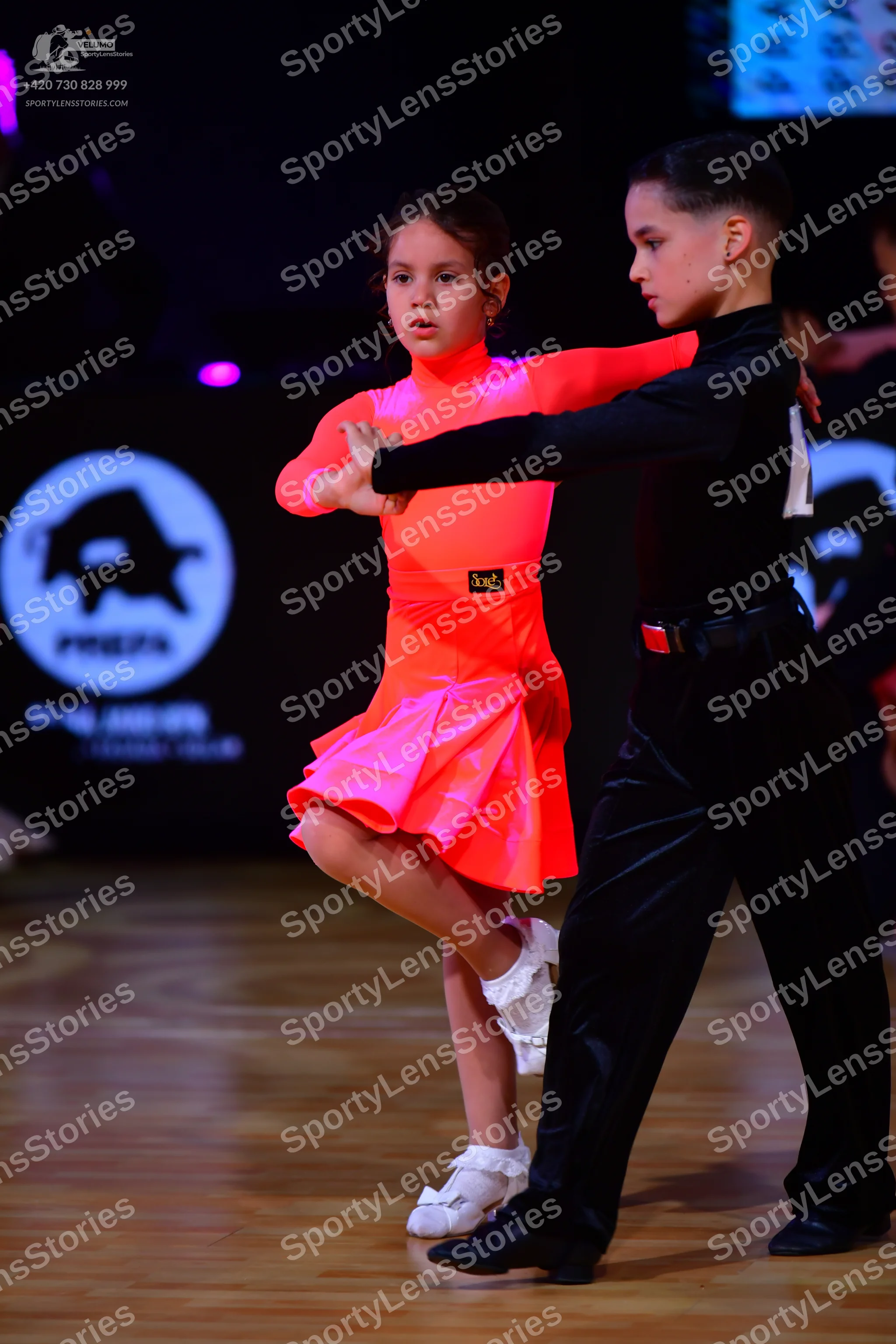Dancesport competitor: Female dancer: neon pink long-sleeved Latin dress with a flared skirt