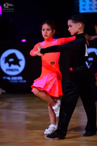 Dancesport competitor: Female dancer: neon pink long-sleeved Latin dress with a flared skirt