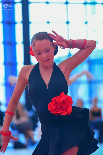 Dancesport competitor: Female dancer: black latin dress with a halter neck, a large red fabric flower a