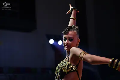 Dancesport competitor: Female dancer: black Latin dance costume with intricate gold sequin/metallic pat