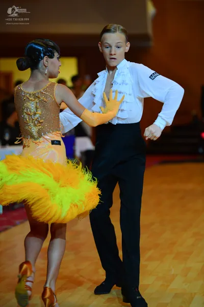 Dancesport competitor: Female dancer: gold/orange sequined latin dance dress with a large, voluminous y
