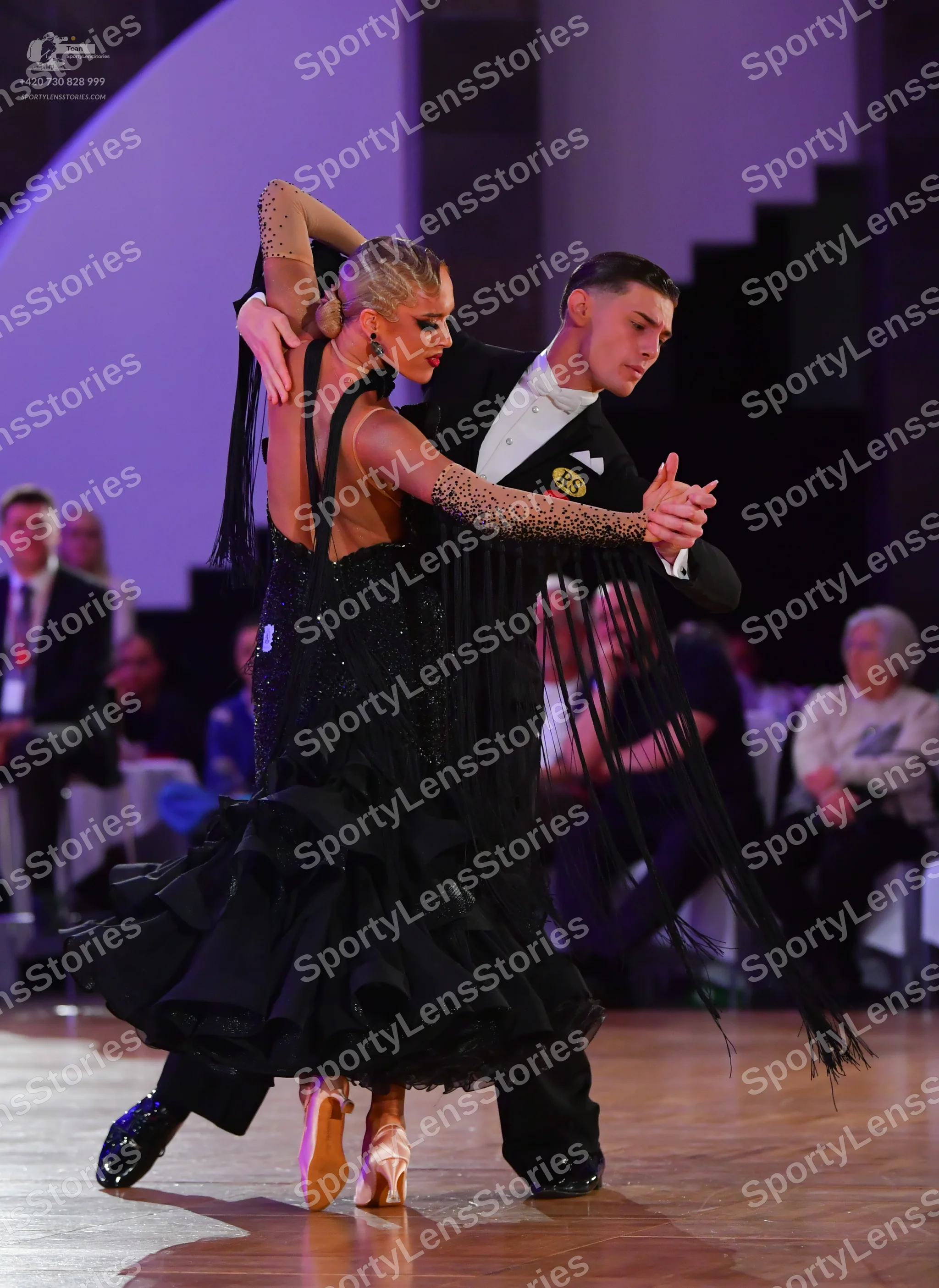 Dancesport competitor: Female dancer: black ballgown with a nude-colored bodice and sleeve covered in b