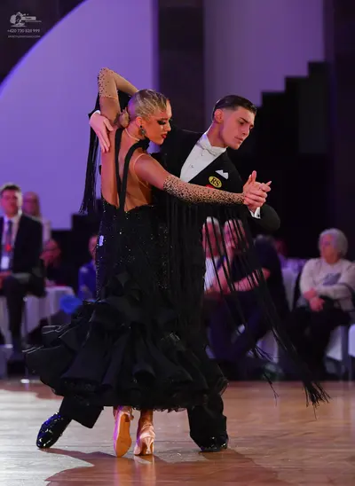 Dancesport competitor: Female dancer: black ballgown with a nude-colored bodice and sleeve covered in b