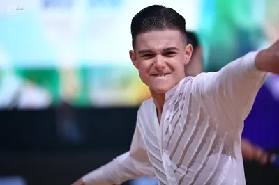 Dancesport competitor: Male dancer in foreground: white long-sleeved latin dance shirt with vertical te