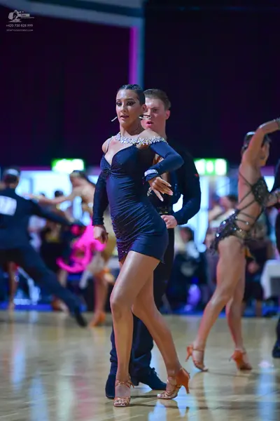 Dancesport competitor: Central female dancer: dark blue long-sleeved latin dress with silver crystal em