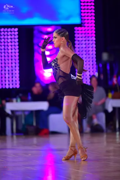 Dancesport competitor: Female dancer: black latin dress with sheer mesh panels, sequin embellishments o