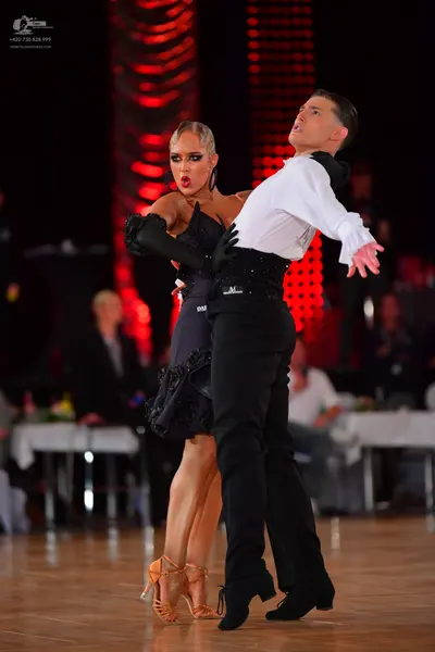 Dancesport competitor: Male dancer: white long-sleeved shirt, black trousers, and a black waistband