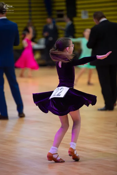 Dancesport competitor: Female (Girl)**: Purple velvet dress with a full, swirling skirt