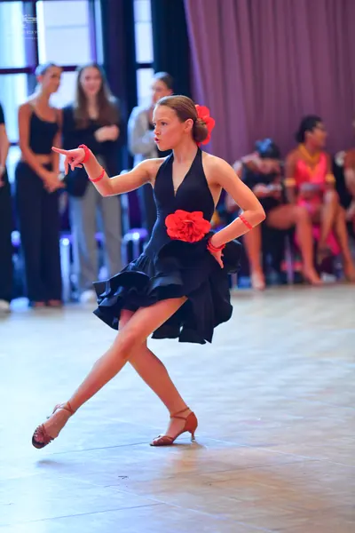 Dancesport competitor: Main female dancer: black latin dress with a halter neckline, a ruffled skirt, a