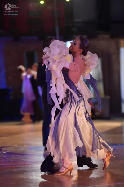 Dancesport competitor: Female dancer: flowing white and lavender ballroom gown with layered, petal-like