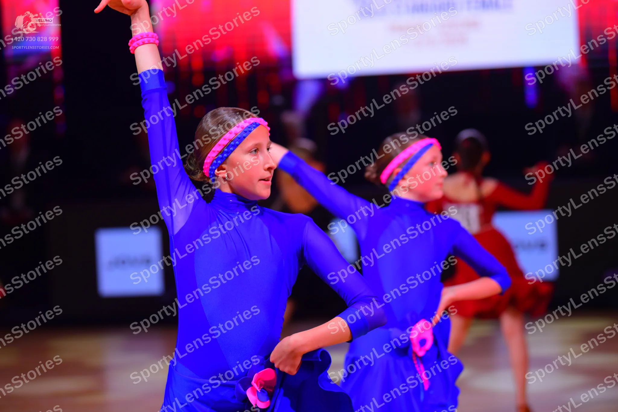 Dancesport competitor: Two dancers are wearing matching blue long-sleeved dance costumes with skirts an
