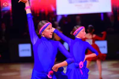 Dancesport competitor: Two dancers are wearing matching blue long-sleeved dance costumes with skirts an
