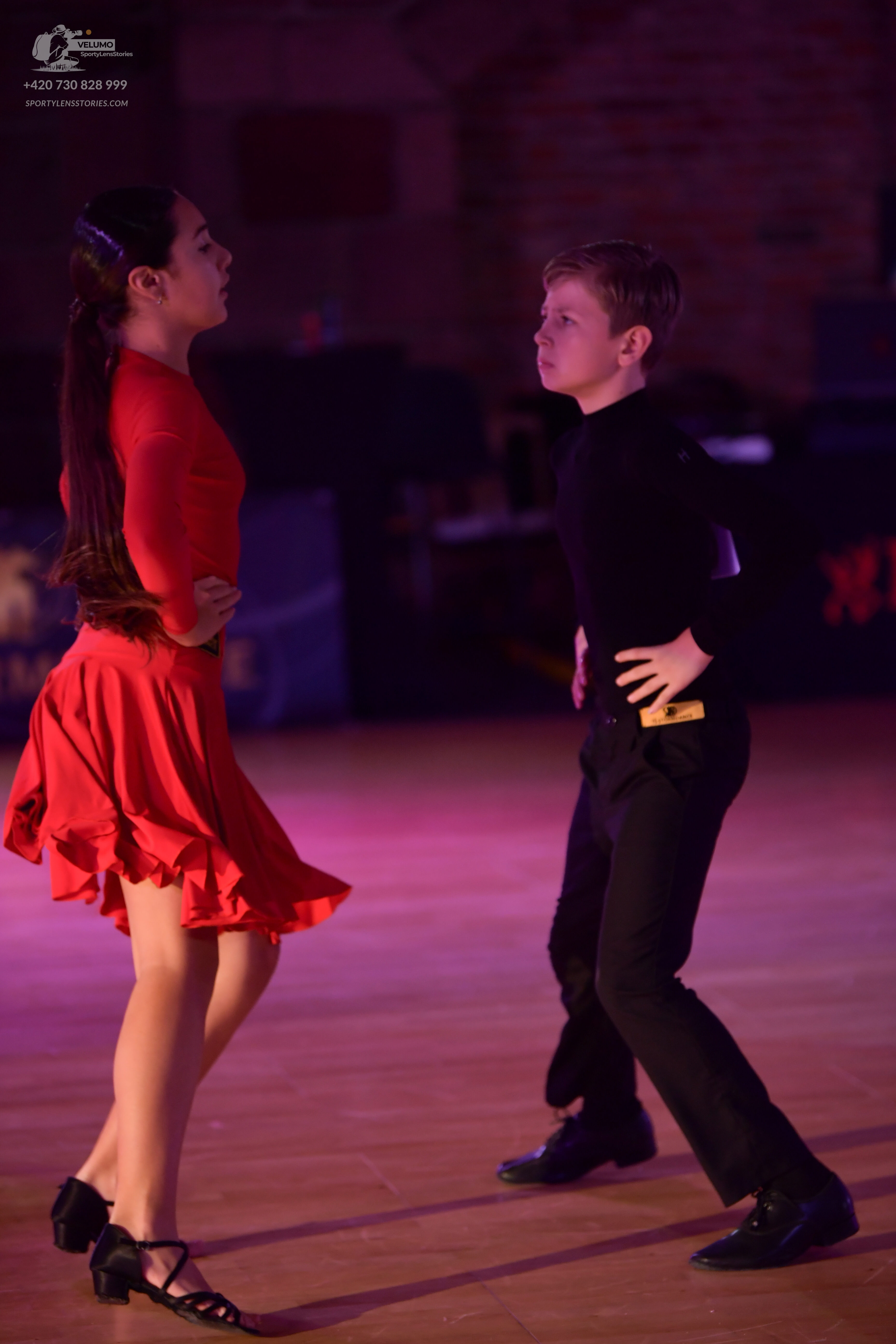 Dancesport competitor: Female dancer: red long-sleeved Latin dress with a flared skirt and black strapp