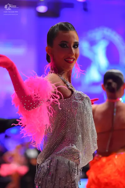 Dancesport competitor: Female dancer: silver sequined latin dress with a pink feathered and rhinestone-