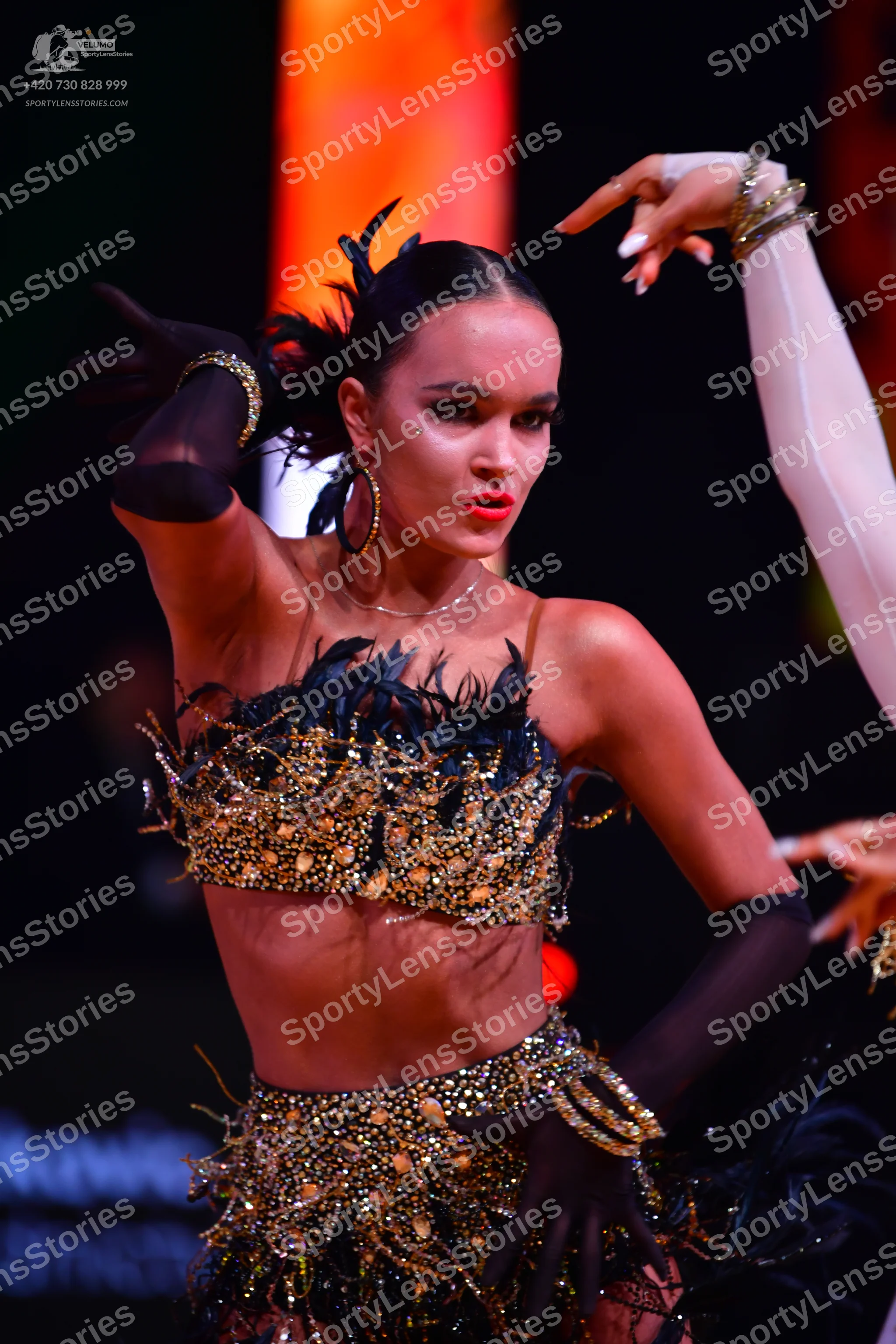 Dancesport competitor: Female dancer: black two-piece Latin dance costume heavily embellished with gold