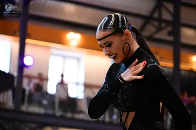 Dancesport competitor: Female dancer: black long-sleeved Latin costume with sequins and large black hoo