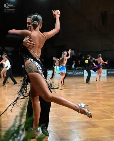 Dancesport competitor: Foreground female dancer: nude-colored latin dress with silver sequins, beads, a