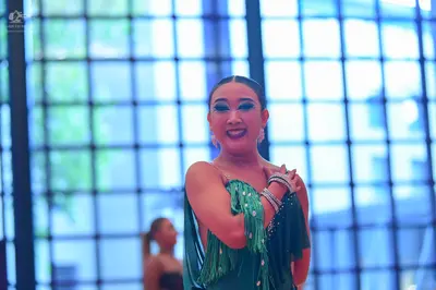 Dancesport competitor: Female dancer in foreground: green latin dress with fringe and silver embellishm