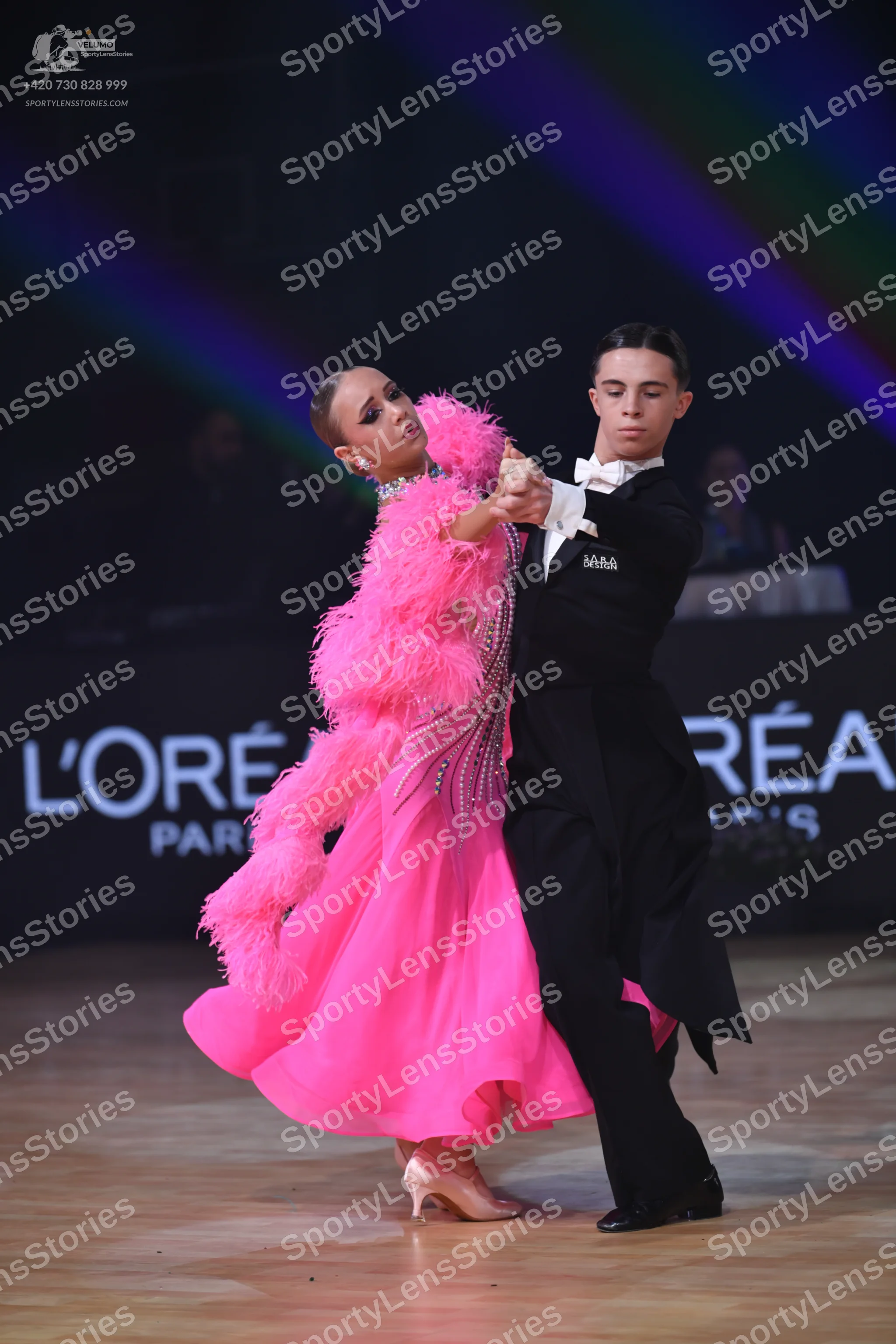 Dancesport competitor: Female dancer: bright pink ballgown with feathery embellishments and a sparkly b