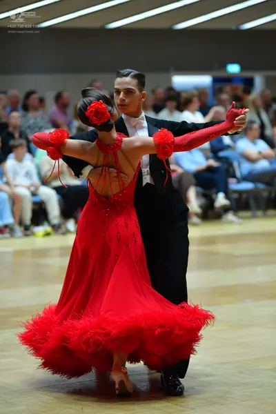 Dancesport competitor: Female dancer: red latin dress with red feather trim at the hem and red floral/r