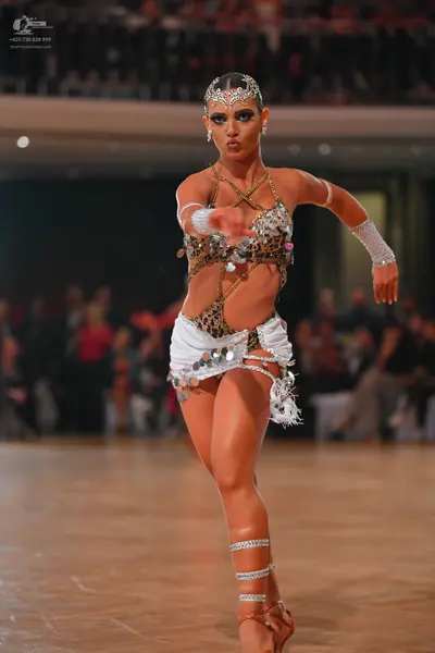 Dancesport competitor: Female dancer: leopard print and gold sequined latin costume with white ruffled/