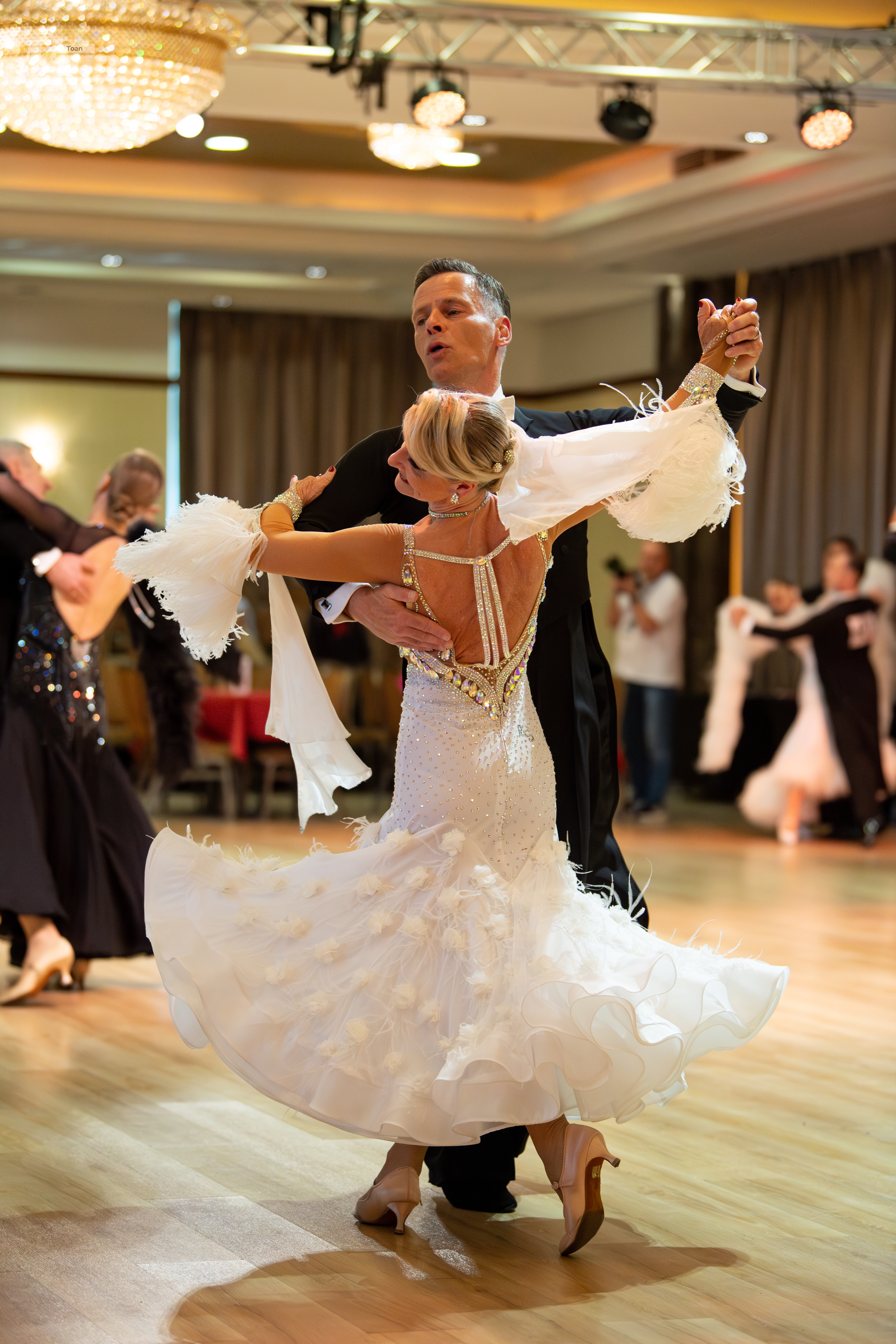 Dancesport competitor: Main female dancer: white ballgown with a voluminous, ruffled/feathery skirt and