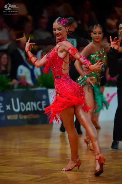 Dancesport competitor: Female dancer 1: red latin dress with sequins and fringe, with red armbands and 