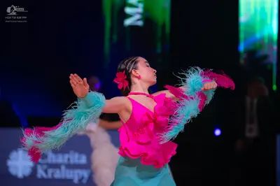 Dancesport competitor: Female dancer: pink latin dress with layers of pink fringe and a teal skirt