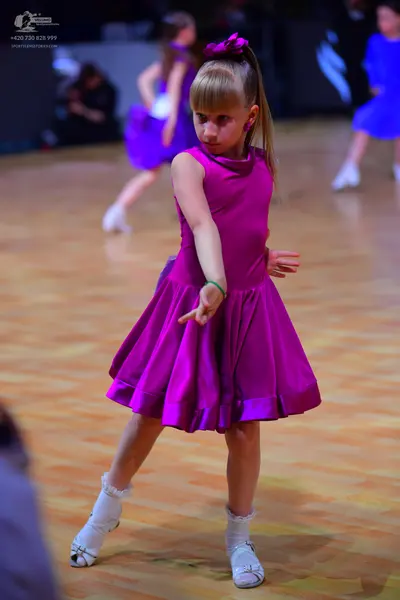 Dancesport competitor: Female dancer (foreground): magenta satin sleeveless A-line dress with a wide he