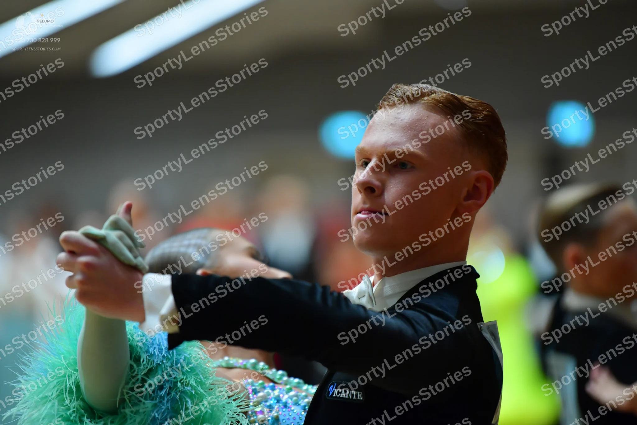 Dancesport competitor: Male dancer: black suit with "PICANTE" text on the sleeve and white shirt cuffs