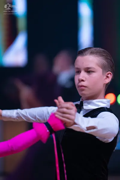 Dancesport competitor: Male dancer: black vest over a white long-sleeved shirt with a black bow tie