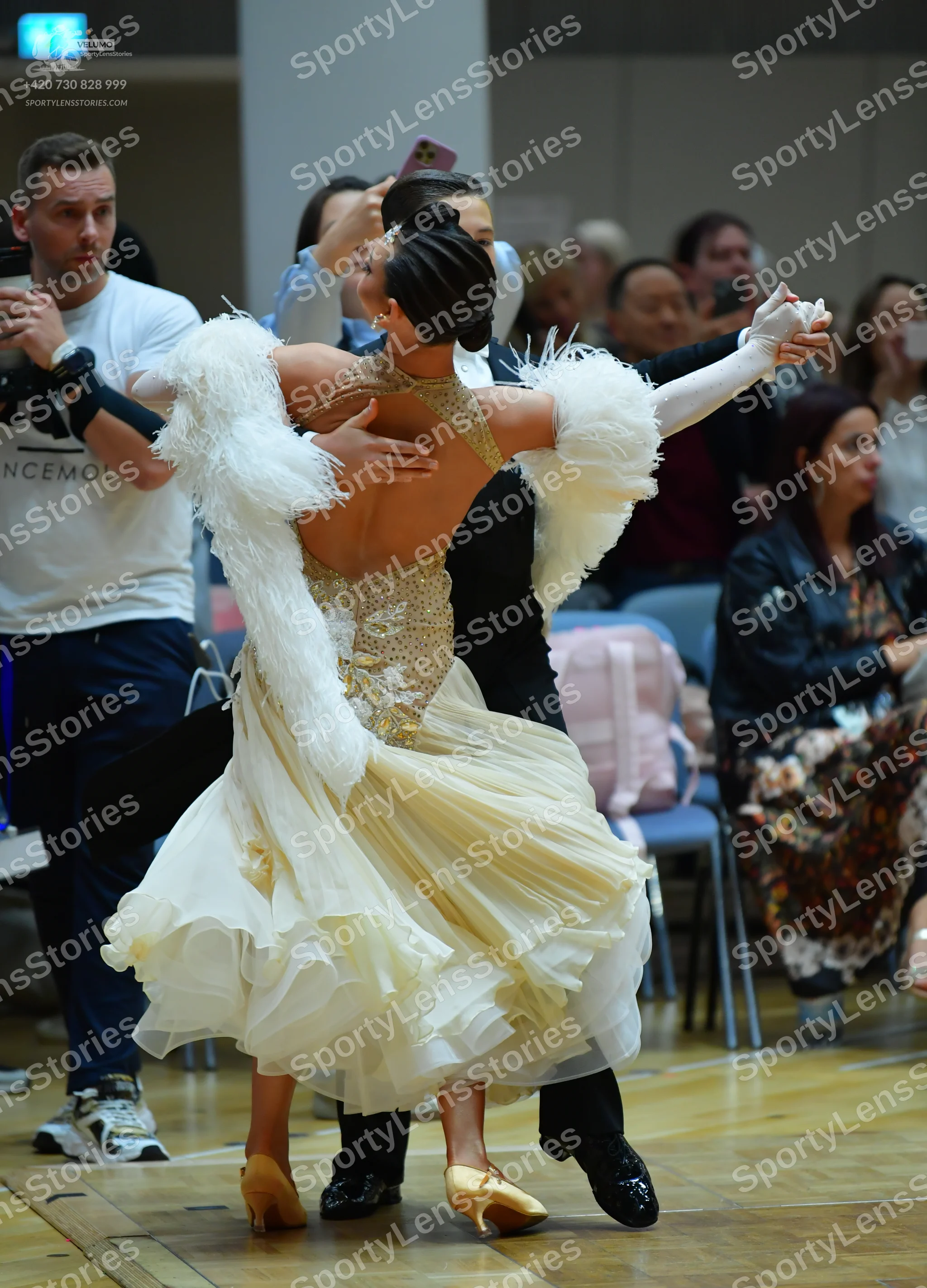 Dancesport competitor: Female dancer: cream-colored ballgown with a sequined bodice, open back, volumin
