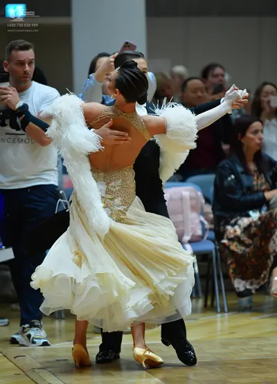 Dancesport competitor: Female dancer: cream-colored ballgown with a sequined bodice, open back, volumin