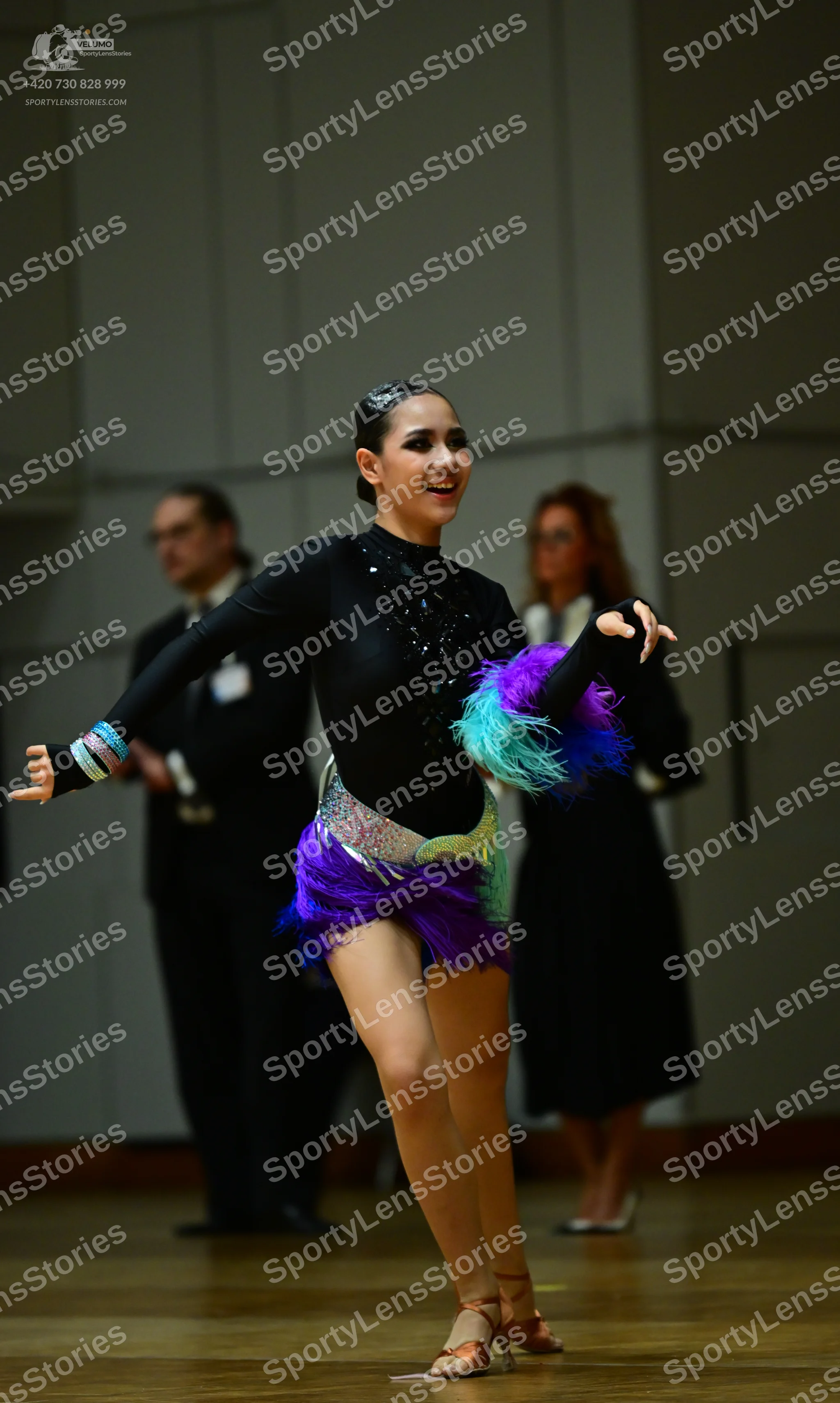 Dancesport competitor: Female dancer (foreground): black long-sleeved Latin dance dress with black sequ