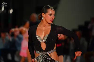 Dancesport competitor: Female dancer: black long-sleeved Latin dress with cutouts, decorated with multi