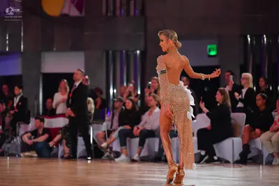 Dancesport competitor: Female dancer: nude-colored Latin dance dress heavily adorned with sequins or cr