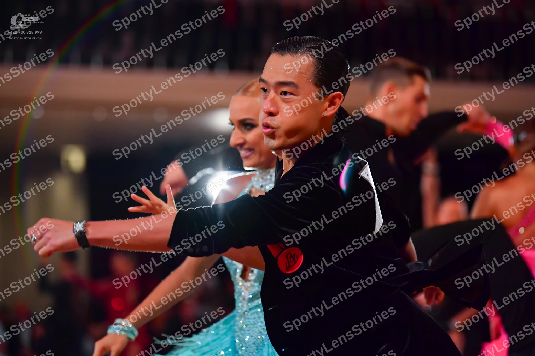 Dancesport competitor: Male dancer: black suit with a red circular ornament