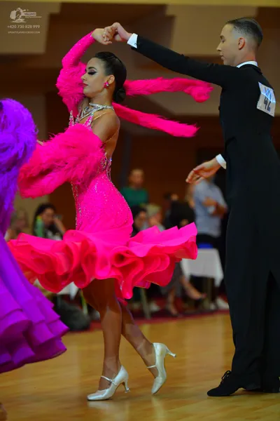 Dancesport competitor: Female dancer: bright pink Latin dress with a sequined bodice, a multi-layered r