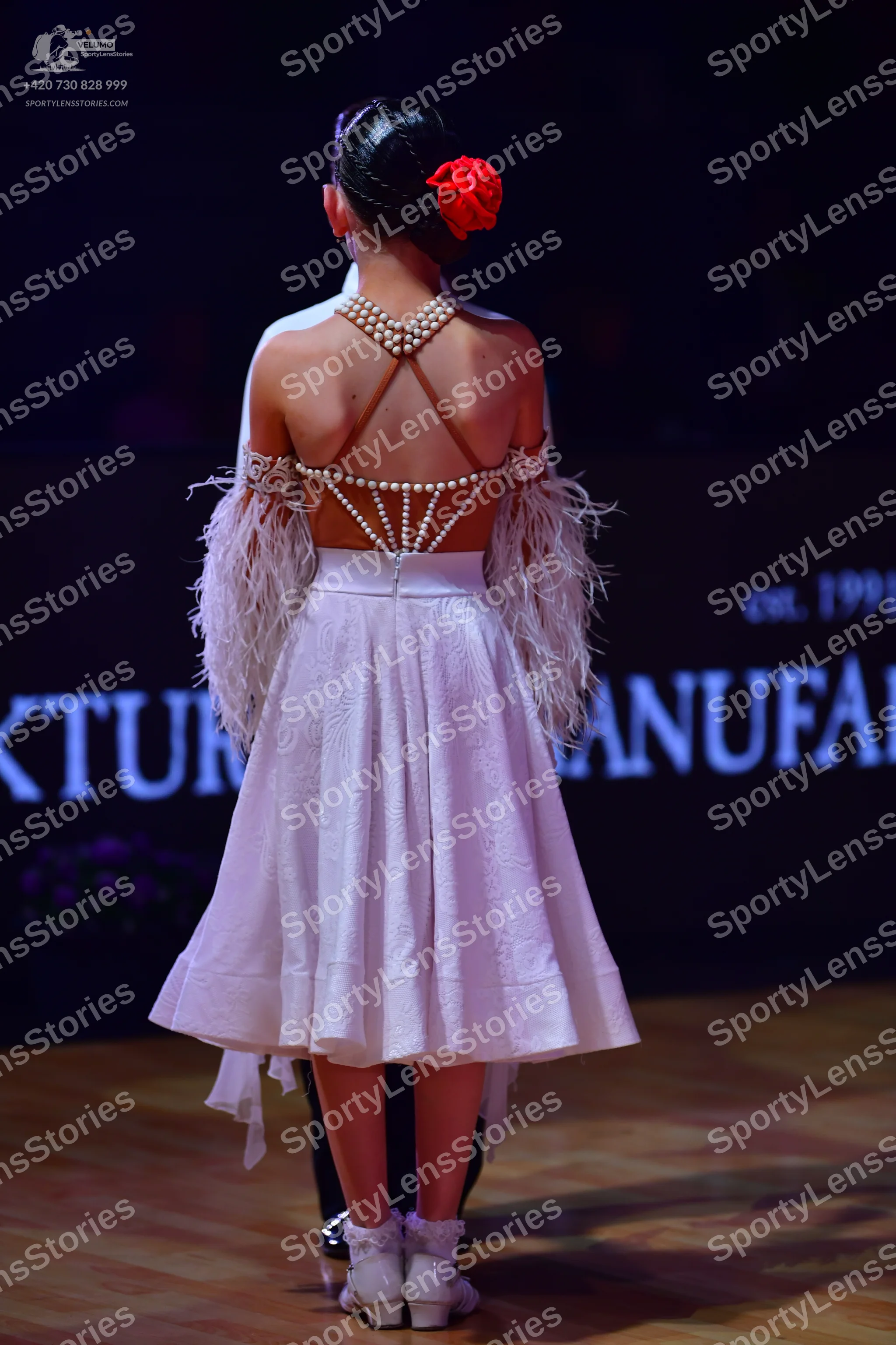 Dancesport competitor: Female dancer: white dress with an open back decorated with pearl-like embellish