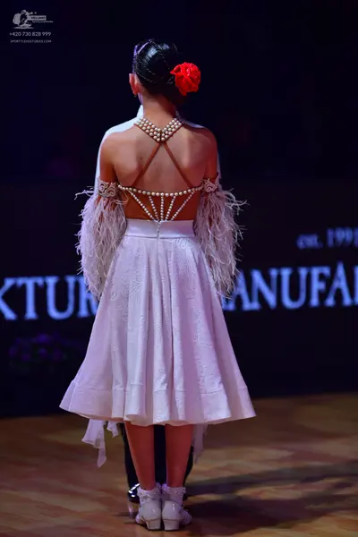 Dancesport competitor: Female dancer: white dress with an open back decorated with pearl-like embellish