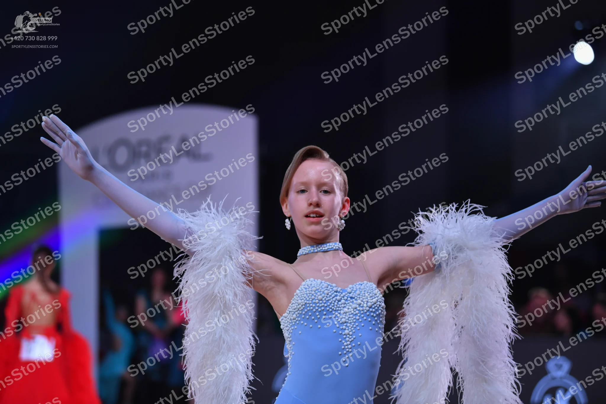 Dancesport competitor: Female dancer in foreground: light blue latin dress with intricate silver/white