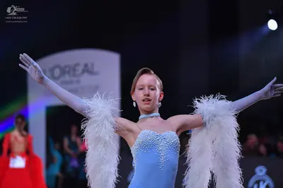 Dancesport competitor: Female dancer in foreground: light blue latin dress with intricate silver/white 
