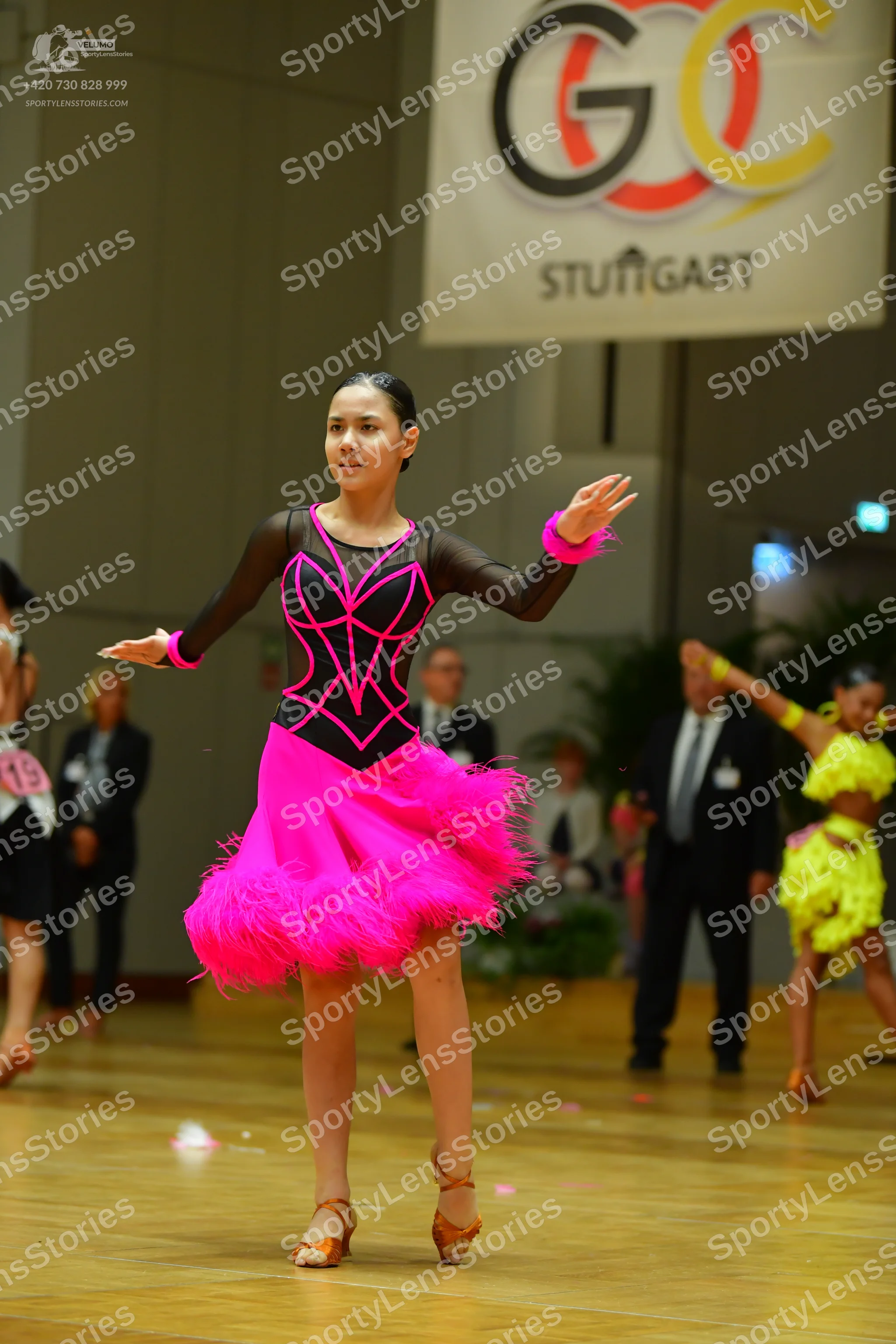 Dancesport competitor: Female dancer: black long-sleeved latin dress with pink trim and a bright pink f