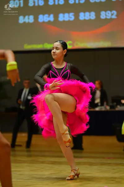 Dancesport competitor: Female dancer: pink and black Latin dress with a large, fluffy pink skirt and bl