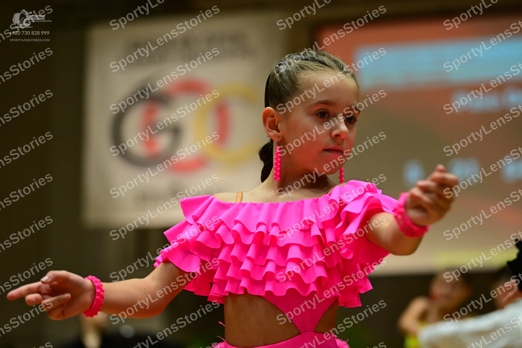 Dancesport competitor: Female dancer: bright pink Latin dance costume with ruffled layers and matching 