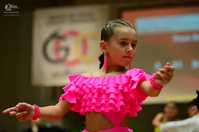 Dancesport competitor: Female dancer: bright pink Latin dance costume with ruffled layers and matching 