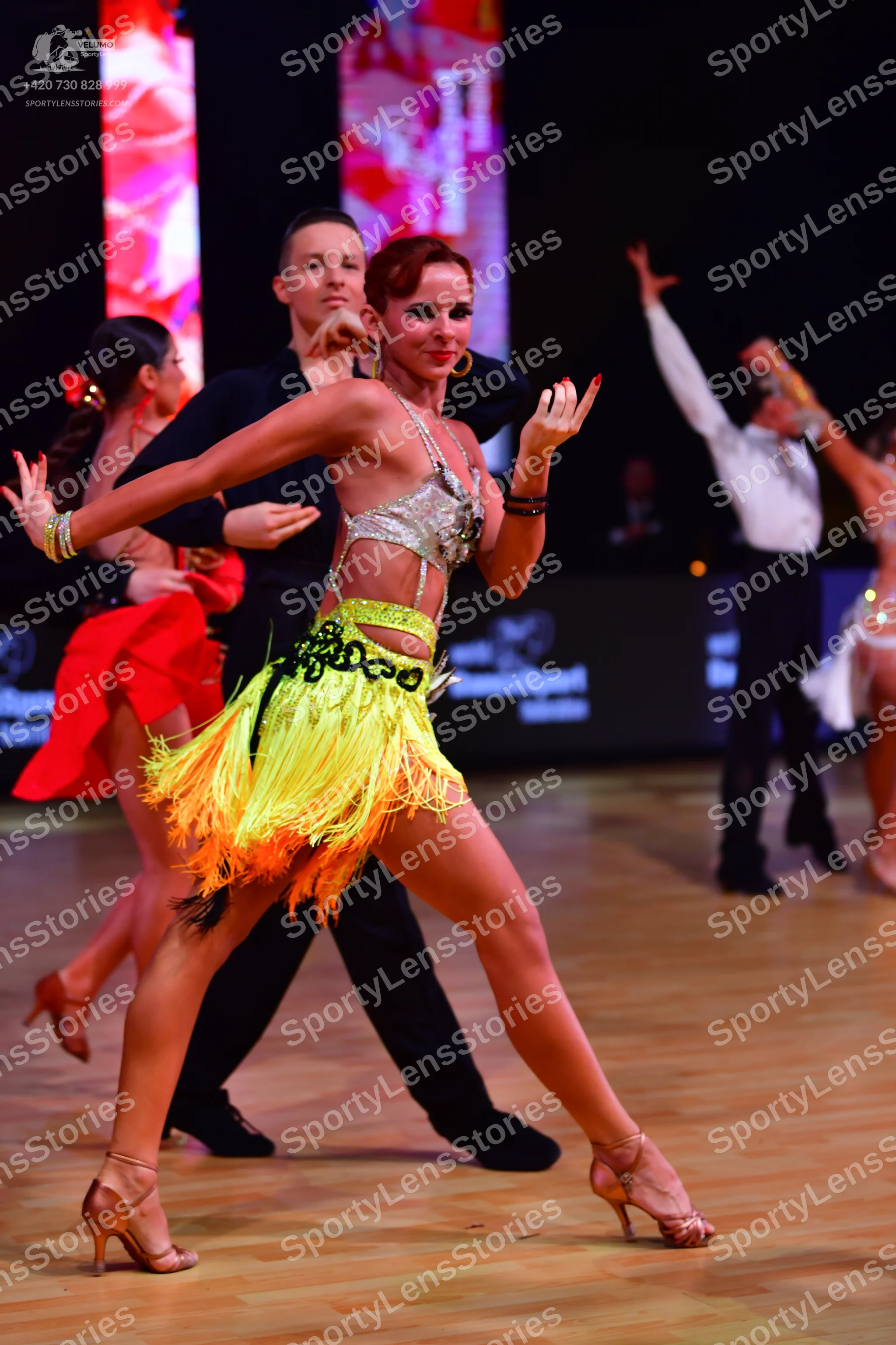 Dancesport competitor: Main female dancer: silver sequined halter top and yellow and green fringed Lati