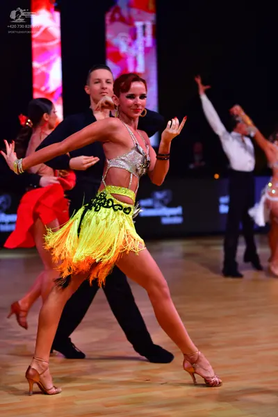Dancesport competitor: Main female dancer: silver sequined halter top and yellow and green fringed Lati