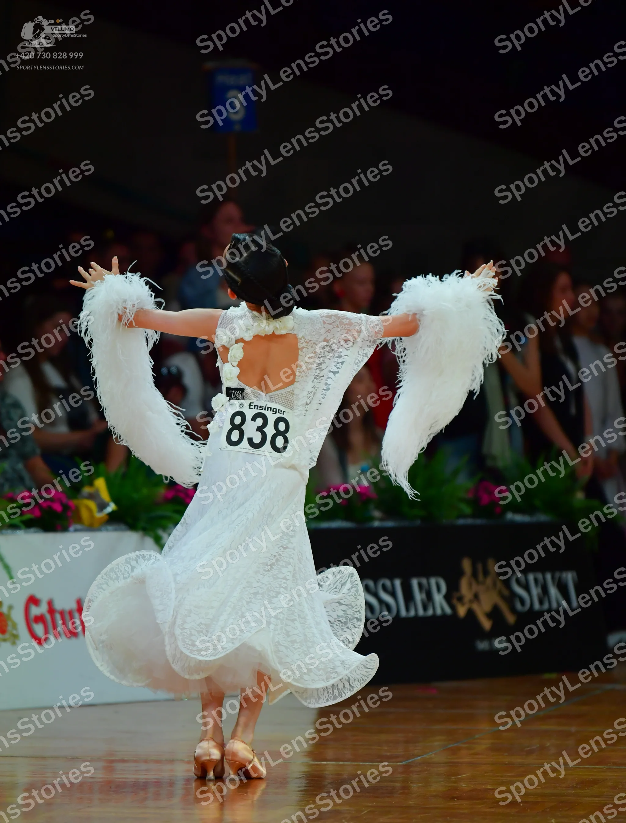 Dancesport competitor: Female dancer: white lace ballroom dress with a large skirt and large white feat