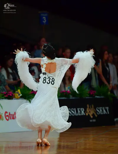 Dancesport competitor: Female dancer: white lace ballroom dress with a large skirt and large white feat